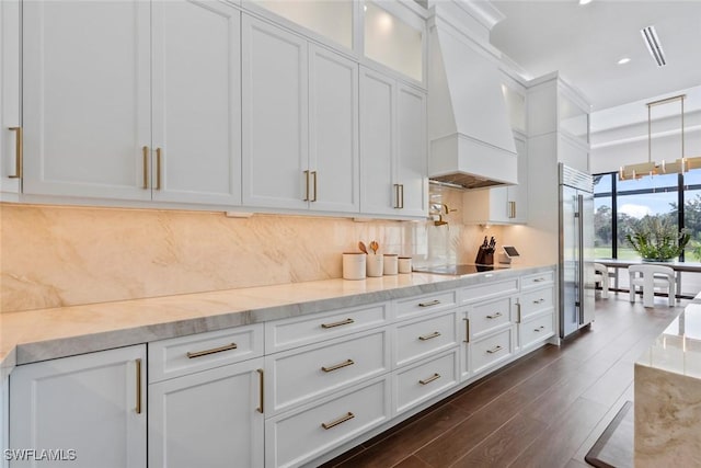 kitchen with premium range hood, white cabinets, decorative backsplash, light stone countertops, and black electric cooktop