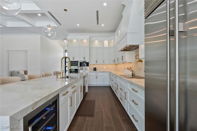 kitchen with white cabinetry, wine cooler, custom exhaust hood, light stone counters, and stainless steel appliances