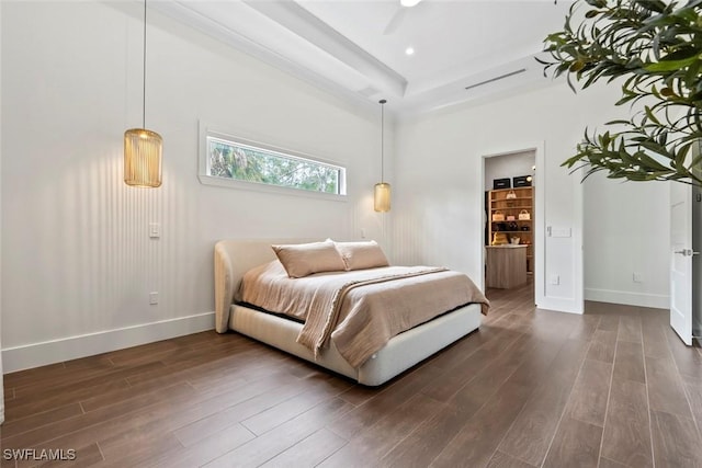 bedroom with dark wood-type flooring, connected bathroom, and a raised ceiling