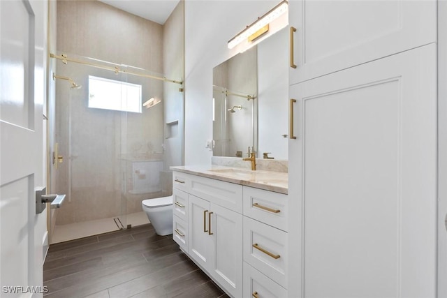 bathroom featuring vanity, toilet, and a tile shower