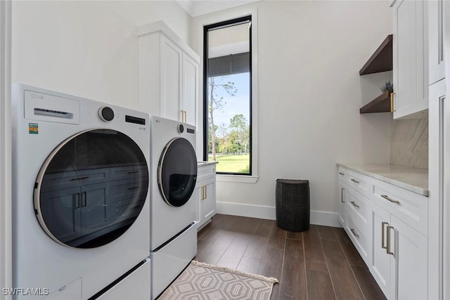 washroom with dark hardwood / wood-style floors, cabinets, and washing machine and clothes dryer