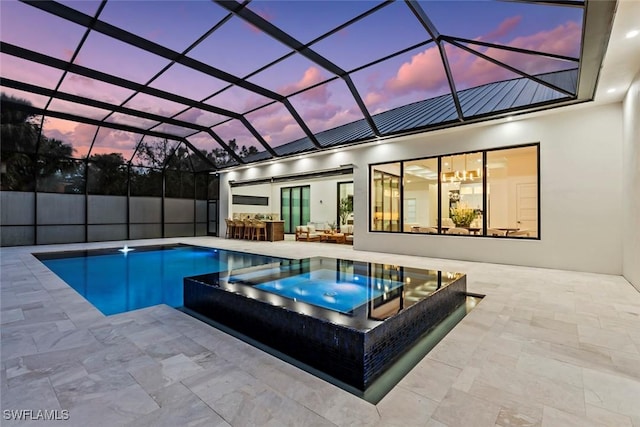 pool at dusk with an in ground hot tub, a lanai, and a patio