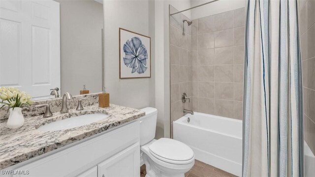 full bathroom featuring hardwood / wood-style flooring, vanity, toilet, and shower / tub combo with curtain