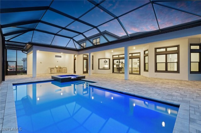 pool at dusk featuring an in ground hot tub, a patio, and a lanai