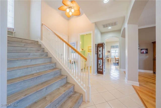 stairs with tile patterned flooring, ceiling fan, and ornamental molding