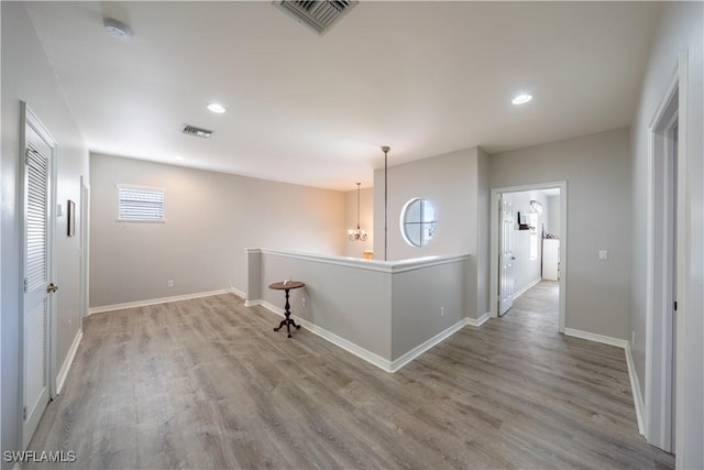 hallway featuring light wood-type flooring and a notable chandelier