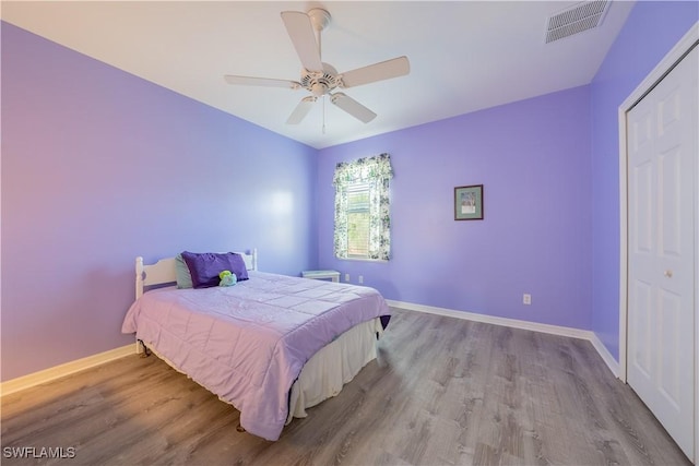 bedroom with ceiling fan, light hardwood / wood-style floors, and a closet