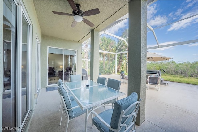 view of patio featuring ceiling fan and glass enclosure