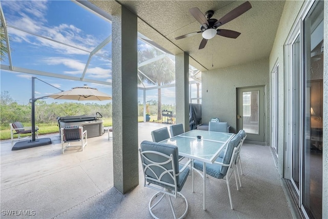 view of patio featuring a hot tub, ceiling fan, and a lanai