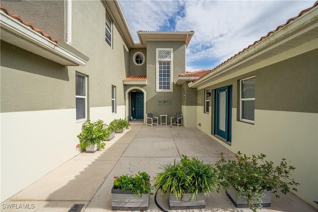 view of exterior entry with a patio area