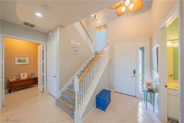 foyer entrance with light tile patterned floors, a wealth of natural light, and ceiling fan