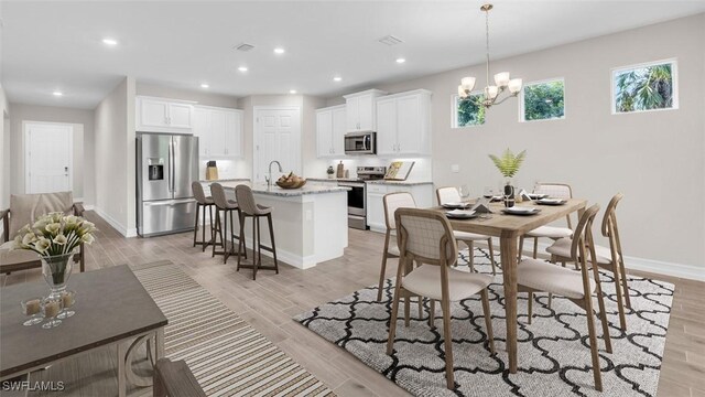 dining area featuring light hardwood / wood-style floors, sink, and an inviting chandelier