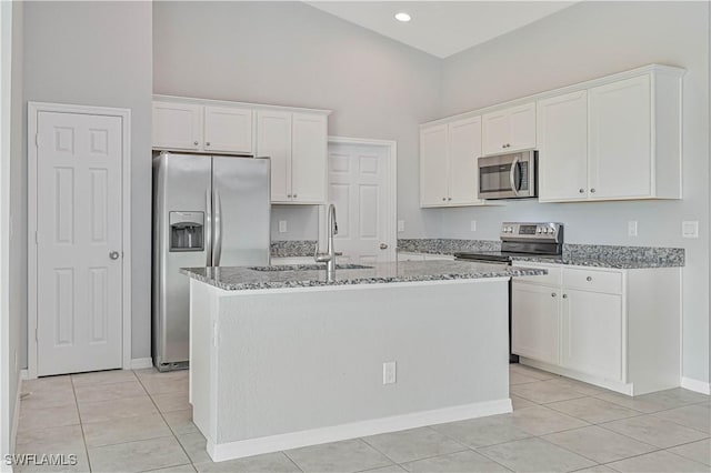 kitchen featuring sink, white cabinetry, stainless steel appliances, light stone countertops, and a center island with sink