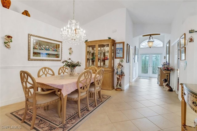 dining space featuring a high ceiling, light tile patterned floors, a notable chandelier, and french doors