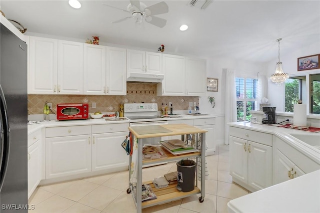 kitchen with white cabinets, white electric range oven, and stainless steel refrigerator