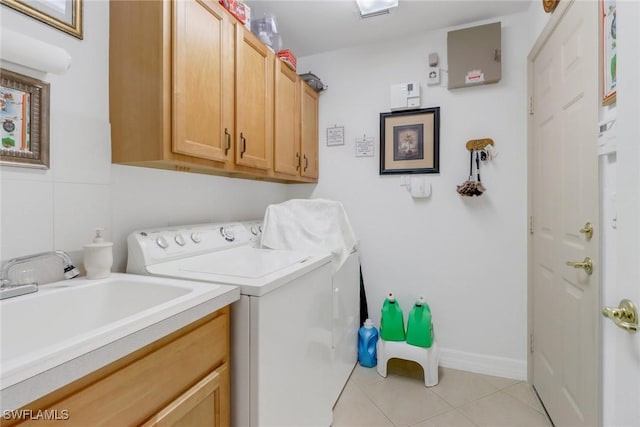 clothes washing area with light tile patterned floors, sink, washer and dryer, and cabinets