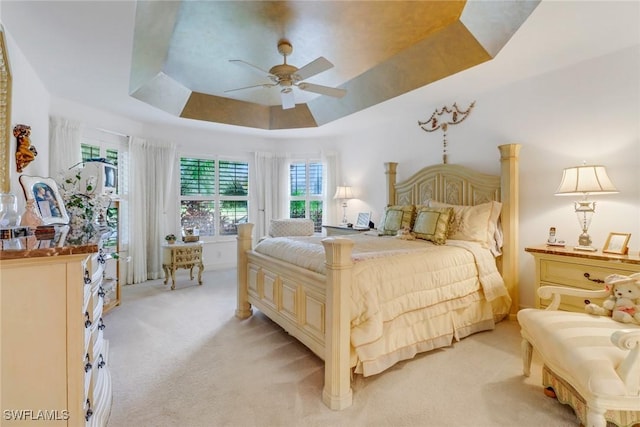 bedroom featuring ceiling fan, light carpet, and a raised ceiling