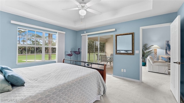 carpeted bedroom with a raised ceiling and ceiling fan