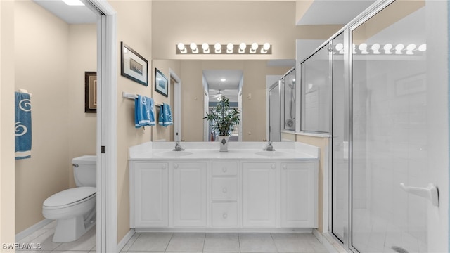 bathroom with tile patterned flooring, vanity, toilet, and a shower with shower door