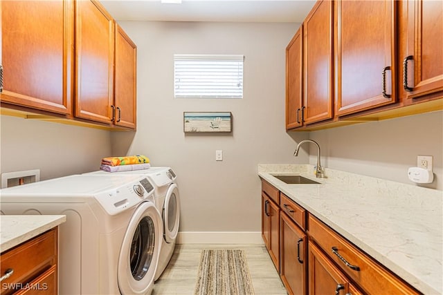 clothes washing area with cabinets, washing machine and dryer, and sink