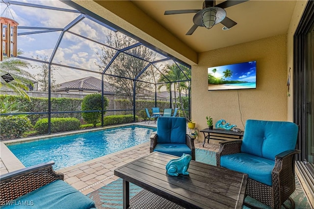 view of swimming pool featuring glass enclosure, ceiling fan, a patio, and an outdoor hangout area