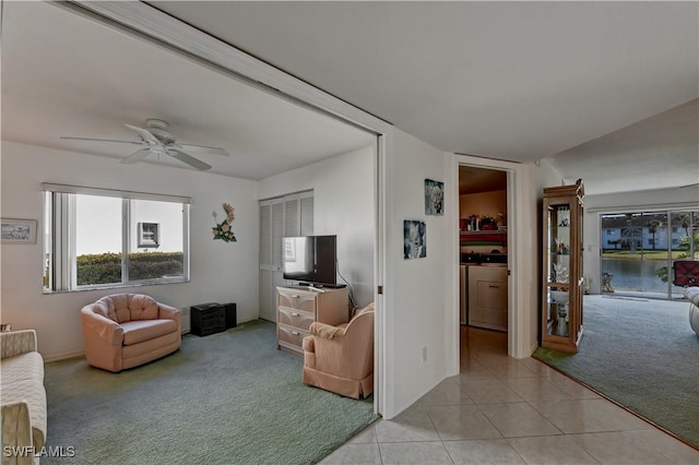 living room with washer / dryer, light colored carpet, and ceiling fan