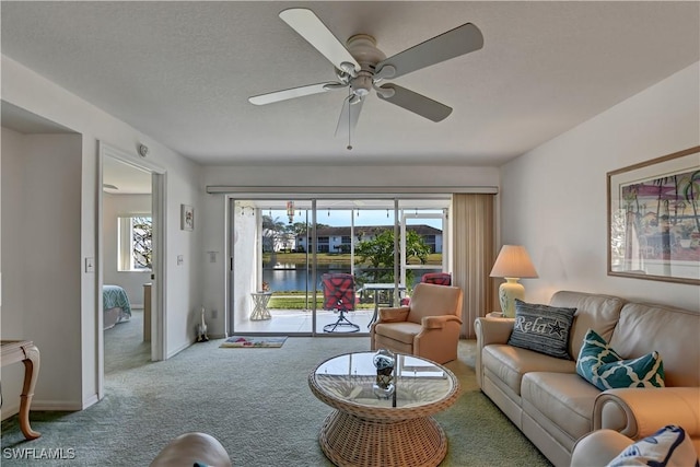 living room featuring carpet, ceiling fan, and a water view