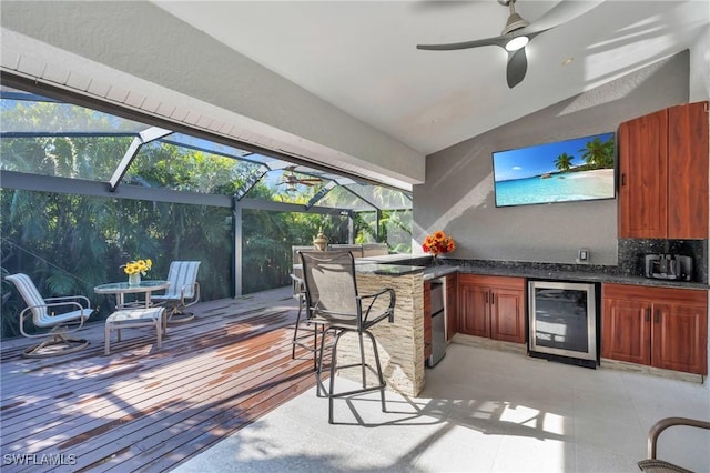 exterior space featuring glass enclosure, exterior kitchen, exterior bar, and wine cooler