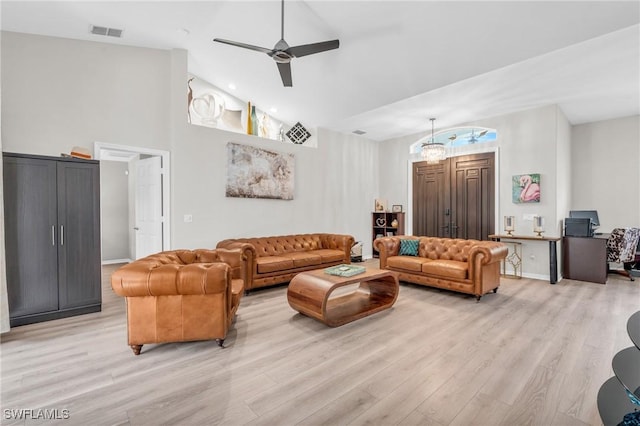 living room with ceiling fan with notable chandelier, light wood-type flooring, and high vaulted ceiling