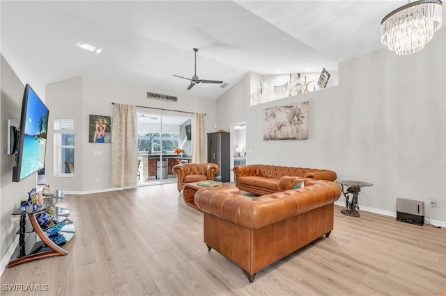 living room featuring ceiling fan with notable chandelier, light wood-type flooring, and lofted ceiling