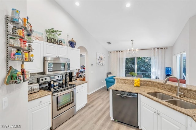 kitchen featuring sink, stainless steel appliances, an inviting chandelier, lofted ceiling, and white cabinets