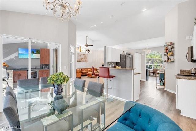 dining area with light hardwood / wood-style floors, beverage cooler, and an inviting chandelier