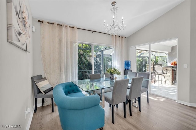 dining room featuring a chandelier, wood-type flooring, vaulted ceiling, and a healthy amount of sunlight