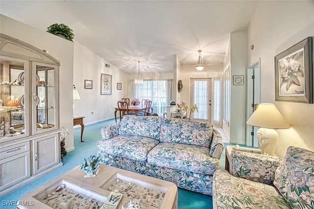 carpeted living room featuring an inviting chandelier