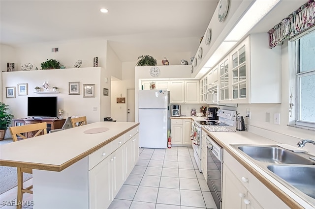 kitchen with a kitchen bar, white appliances, sink, light tile patterned floors, and white cabinets