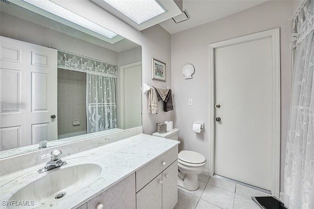 bathroom with tile patterned flooring, vanity, toilet, and a skylight