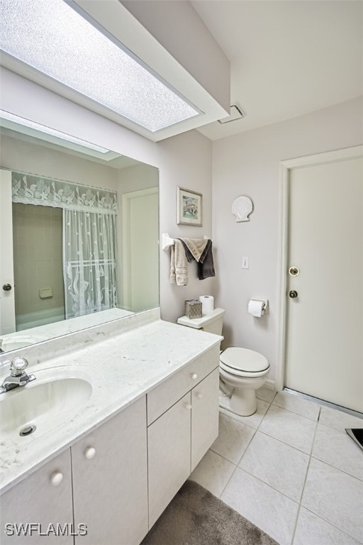 bathroom with tile patterned floors, vanity, toilet, and a skylight