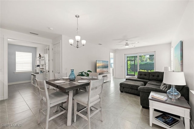 dining area with ceiling fan with notable chandelier, a wealth of natural light, and light tile patterned floors