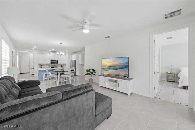 living room featuring ceiling fan with notable chandelier and light tile patterned floors