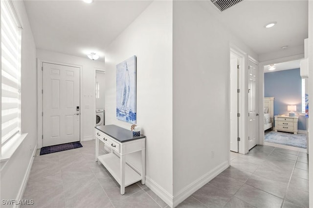 hall with washer / clothes dryer and light tile patterned flooring