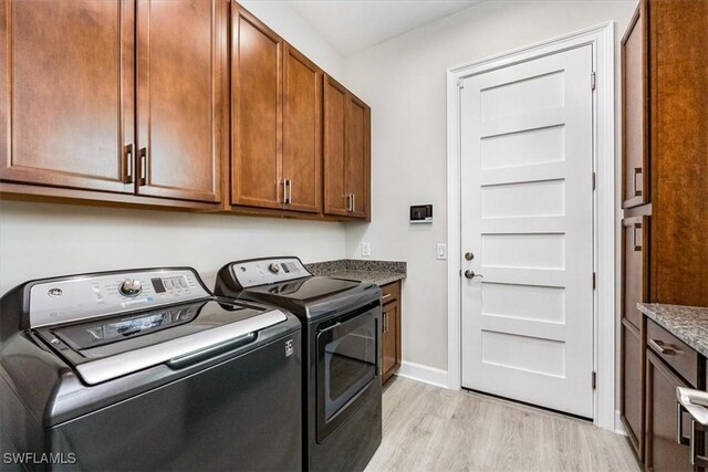 clothes washing area featuring separate washer and dryer, cabinets, and light wood-type flooring