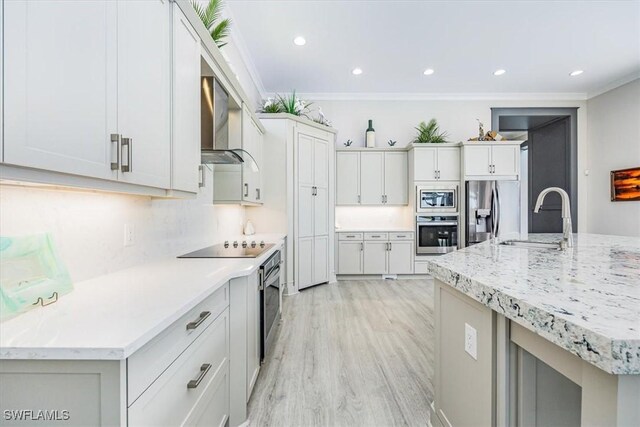 kitchen featuring a center island with sink, crown molding, wall chimney exhaust hood, appliances with stainless steel finishes, and white cabinetry