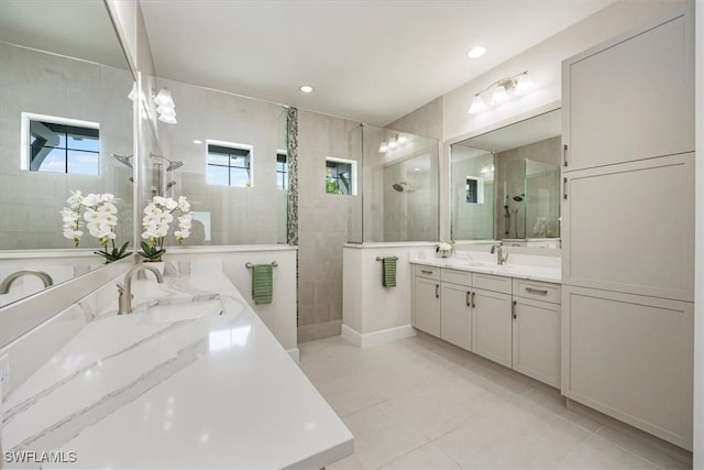 bathroom featuring tiled shower, vanity, tile patterned flooring, and a wealth of natural light