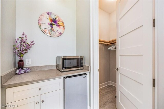 interior space featuring white cabinets, hardwood / wood-style floors, and refrigerator