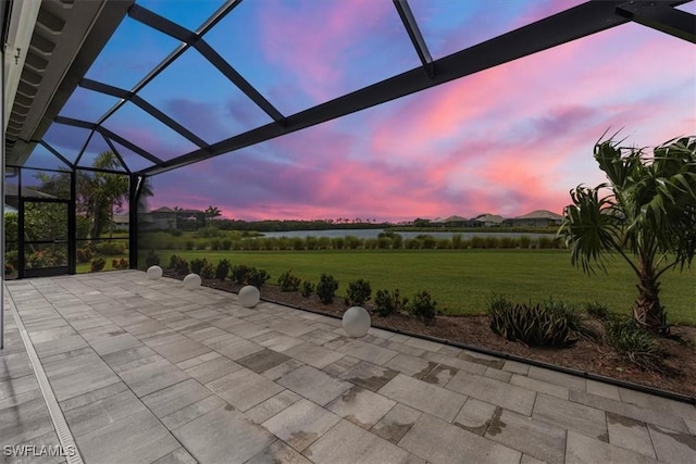 patio terrace at dusk featuring a lanai and a yard