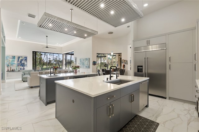 kitchen featuring appliances with stainless steel finishes, sink, a kitchen island with sink, ceiling fan, and gray cabinetry