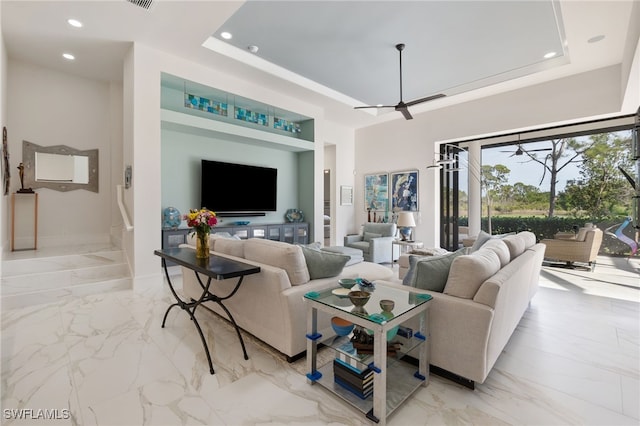 living room featuring a raised ceiling and ceiling fan