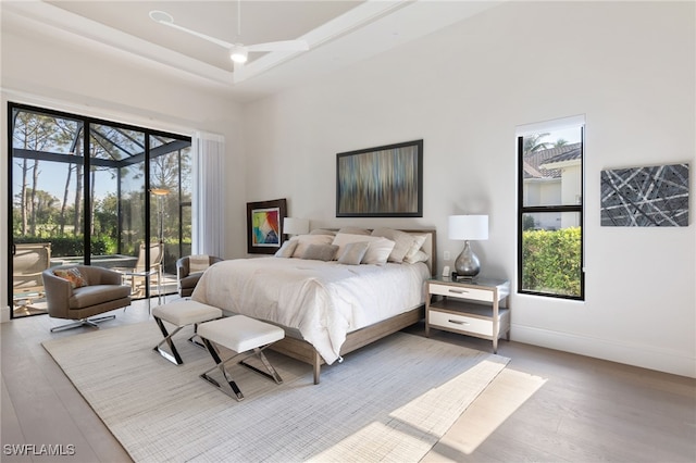 bedroom featuring ceiling fan, wood-type flooring, and a towering ceiling