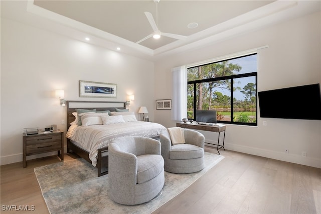 bedroom with light hardwood / wood-style floors and a raised ceiling