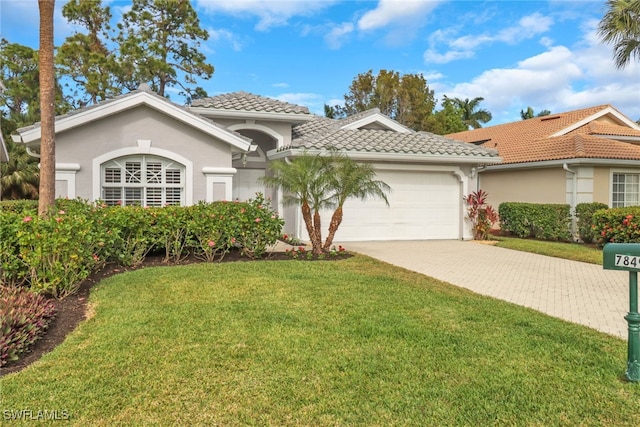 mediterranean / spanish home featuring a garage and a front lawn